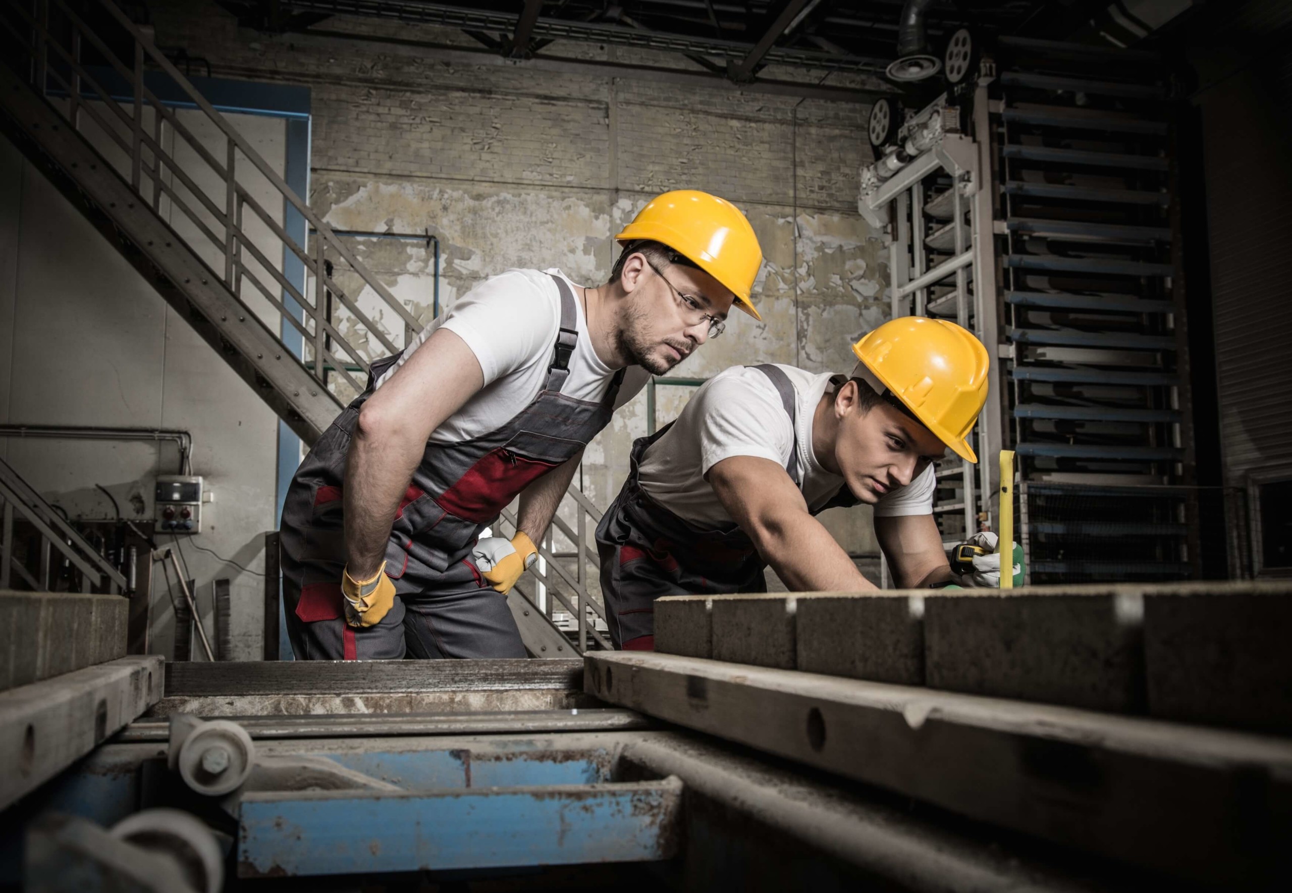 Worker and foreman in a safety hats performing quality check on a factory